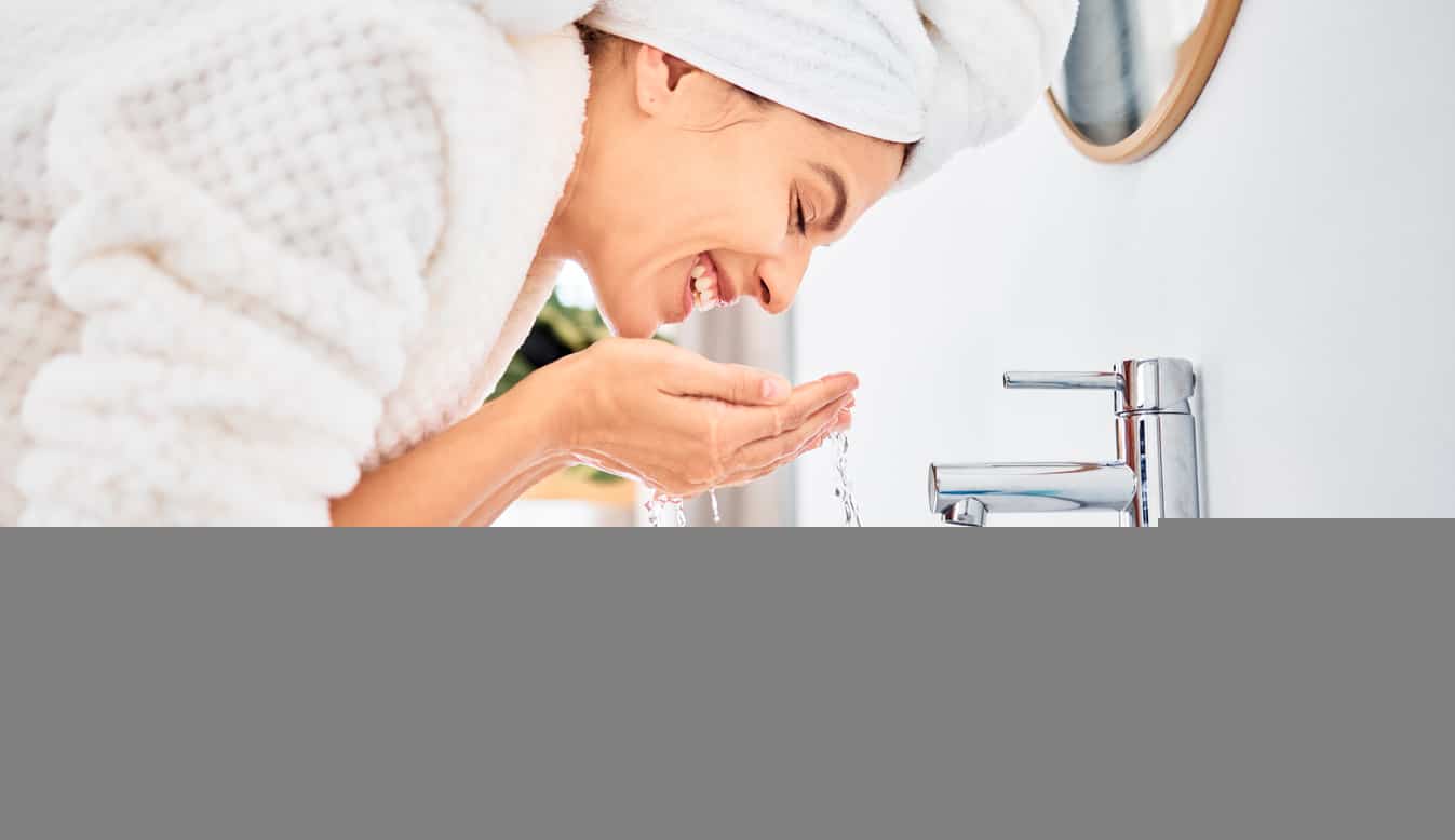Shot of a young woman washing her face in her bathroom
