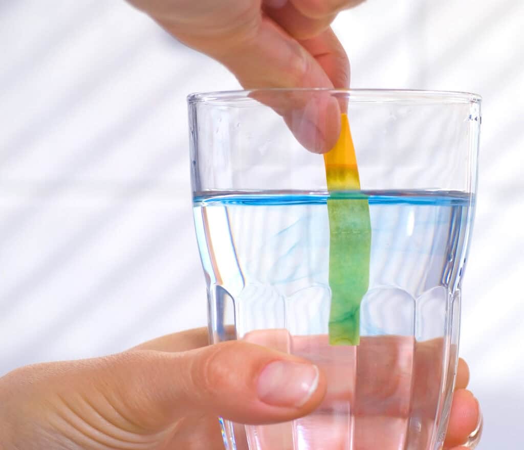 someone testing the ph of their water to see if they have alkaline water or not