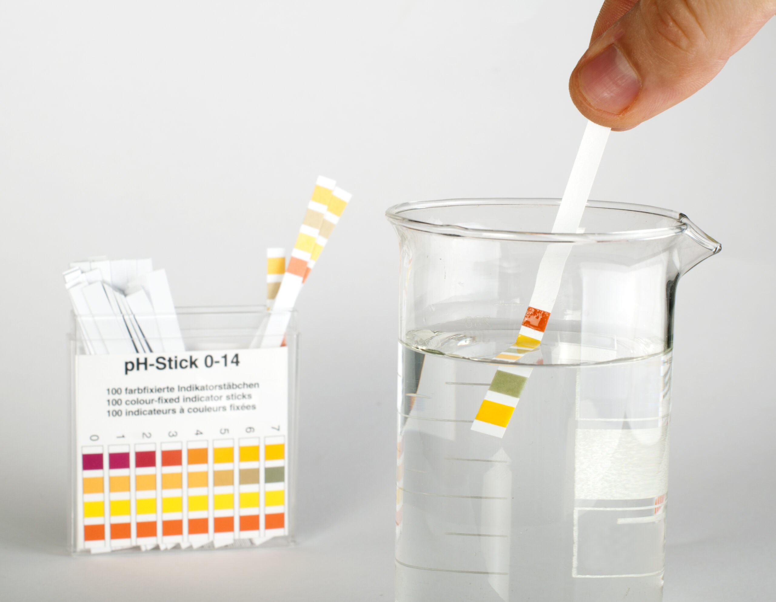 Litmus strips for measurement of acidity in a beaker with water